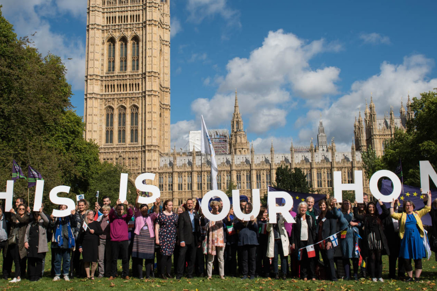 A group of people in front of Houses of Parliament holding up big letters saying &quot;This is our home&quot;