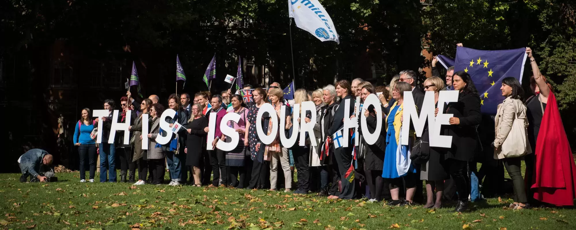 Group of people holding letters spelling "This is our home"