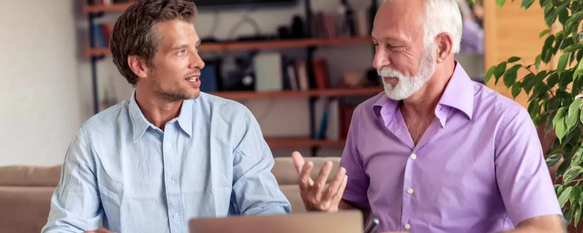 A young man explaining something to a man with white hair