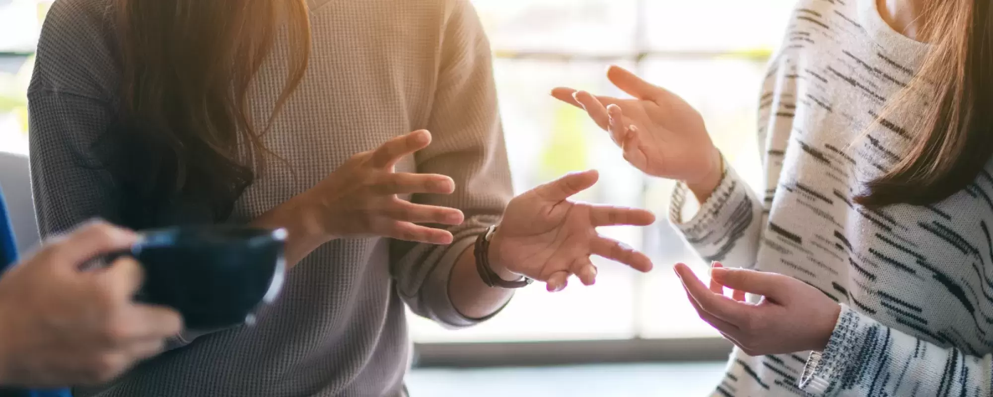 Women talking, focus is on their hands