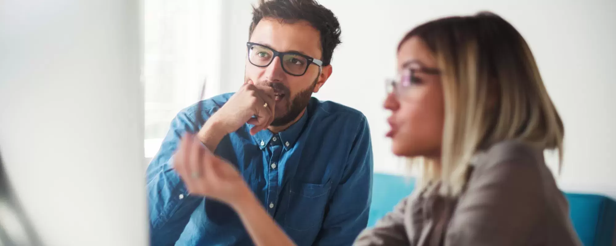 A woman explaining to a man information that is on a PC screen