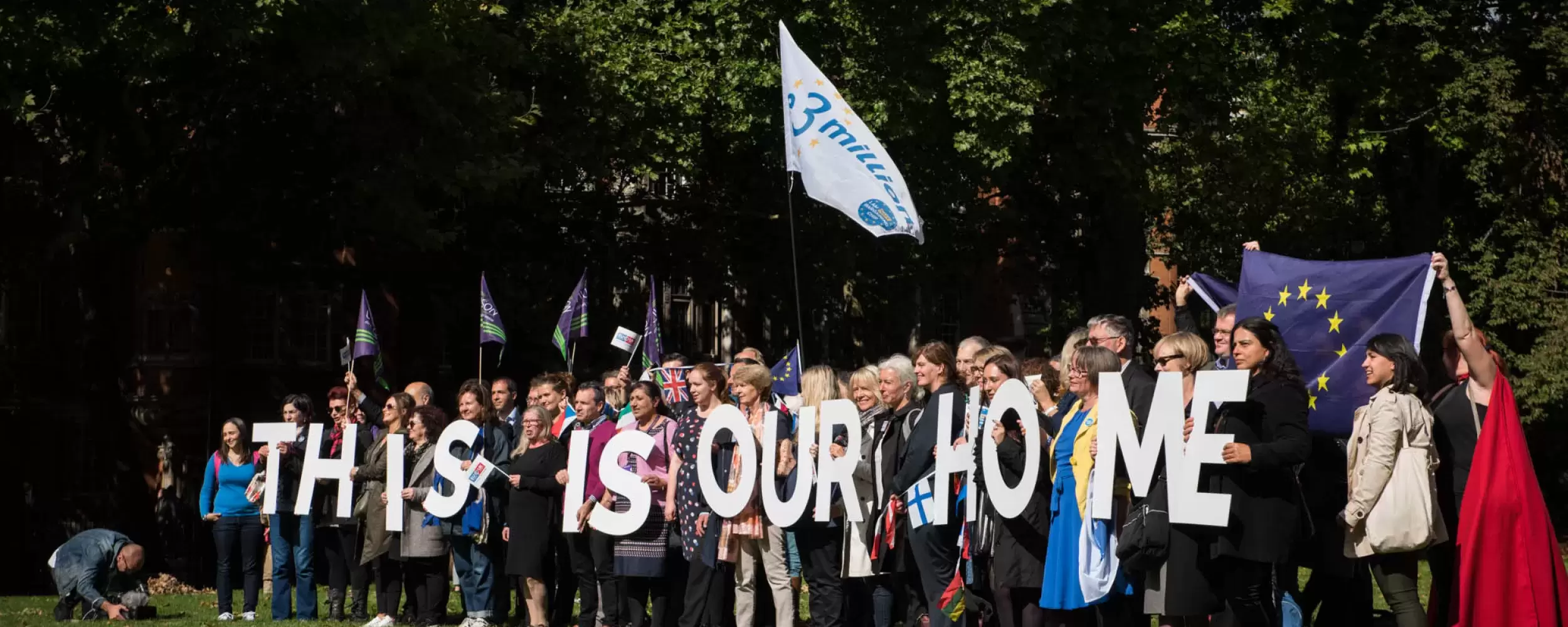 Group of people holding letters spelling "This is our home"