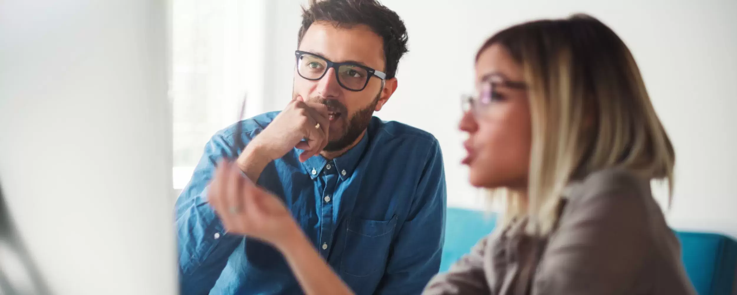 A woman explaining to a man information that is on a PC screen