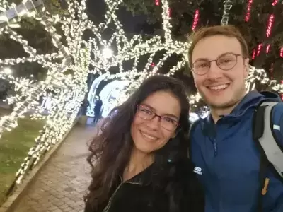 Julia and her husband smiling at the camera with fairy lights in the background
